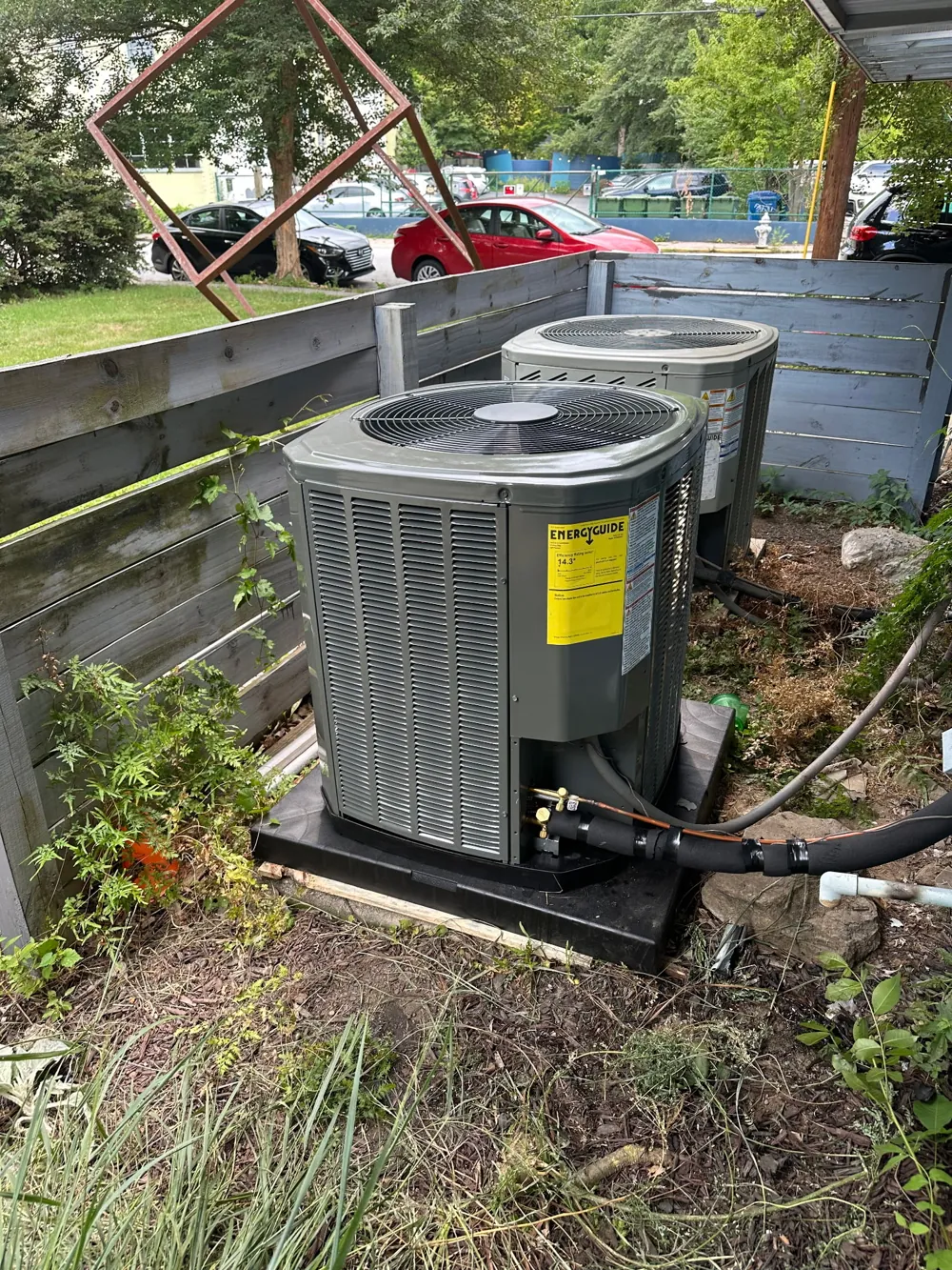 Two newly installed air conditioner condensers beside a wooden fence at a metro Atlanta home