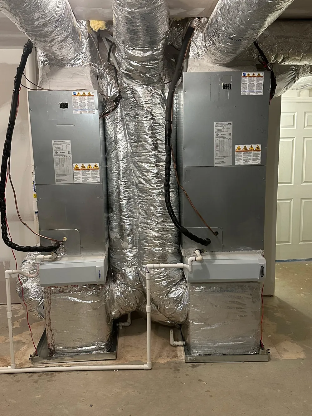 Two new air handlers with insulated ductwork installed in a utility room