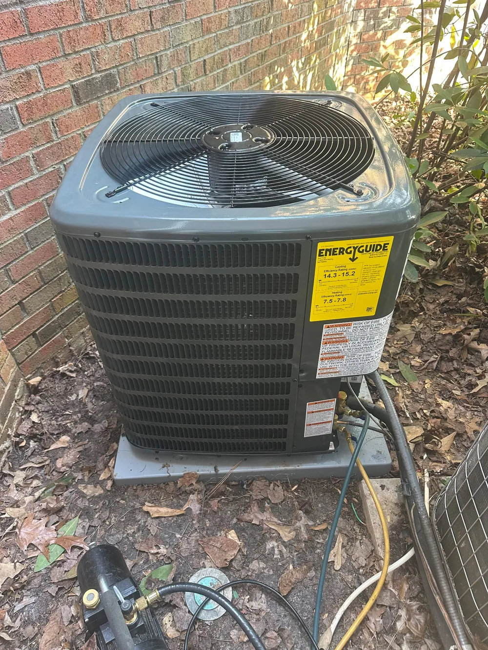 New heat pump outdoor unit installed against a brick wall at an Atlanta-area home