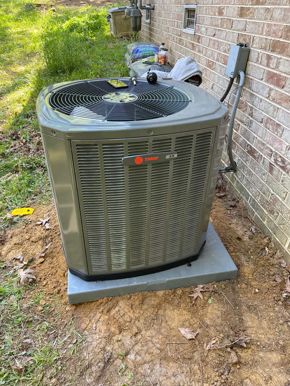 Newly installed Trane air conditioner condenser on a concrete pad beside a brick home in metro Atlanta